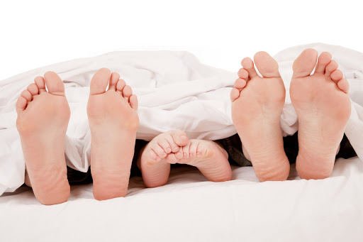 a close up of a family showing off their feet under the covers.