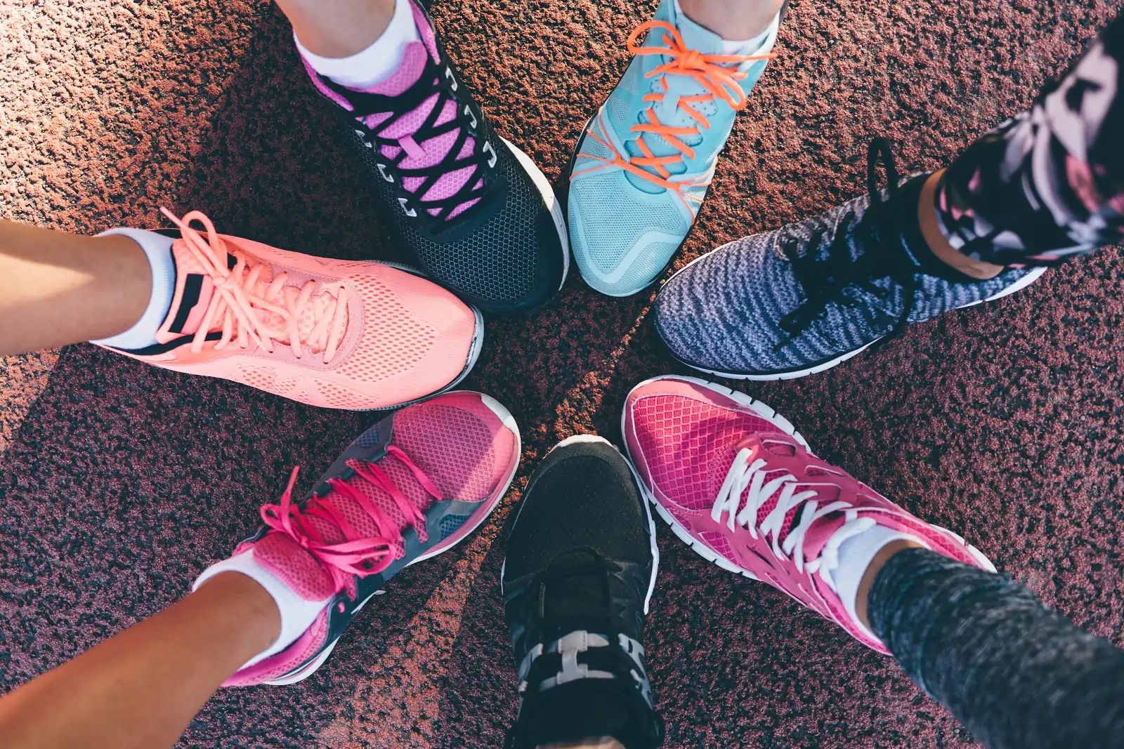 A group of people posing using their foot in an arranged circle on the ground.