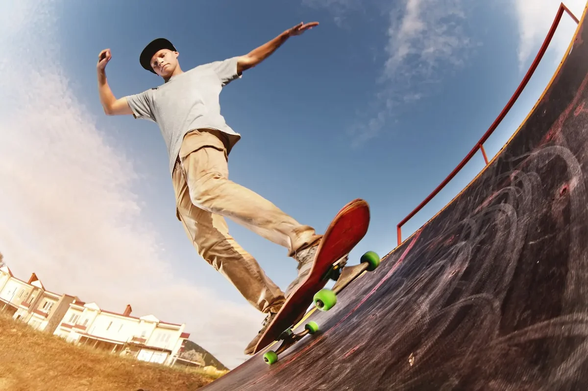 A skateboarder performing a trick along a paved surface from worm's-eye view.