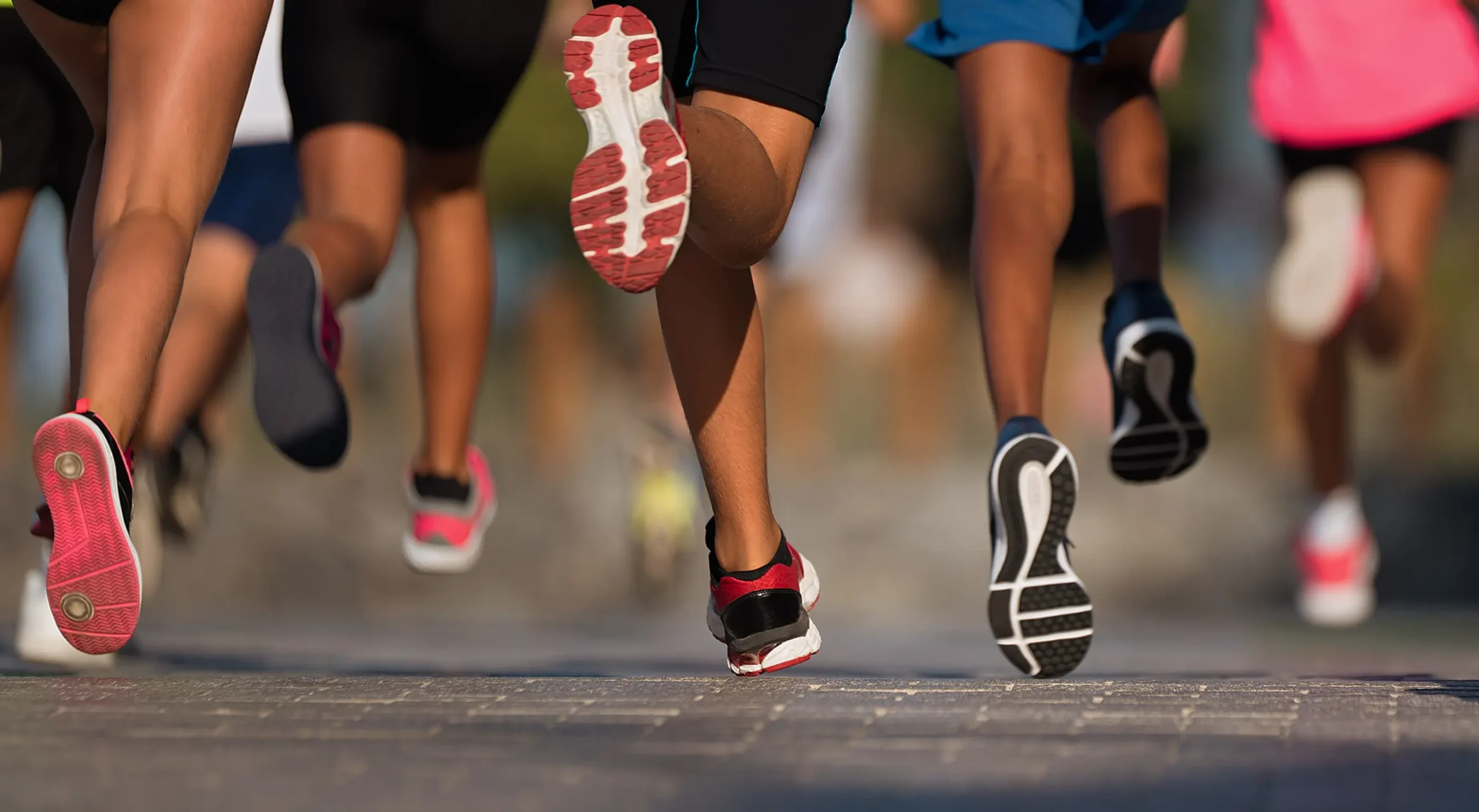 Several pairs of feet mid-stride, taken from ground view during a marathon.