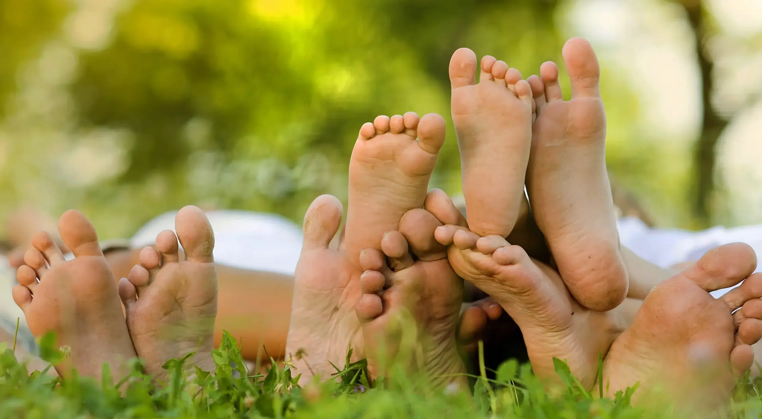 A family lying in the grass, the soles of their visible visible.